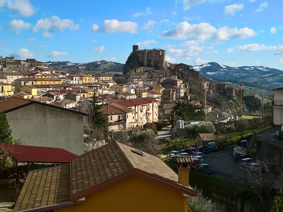 Il borgo di Oriolo con il castello sulla rupe, e le montagne innevate sullo sfondo